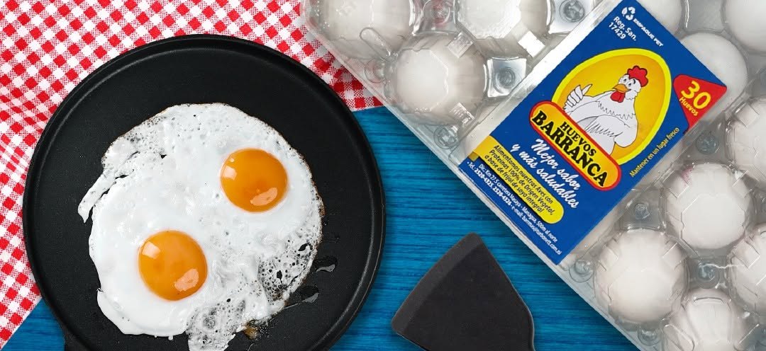 Huevos Barranca en empaque PET de 30 unidades junto a un sartén con huevos fritos